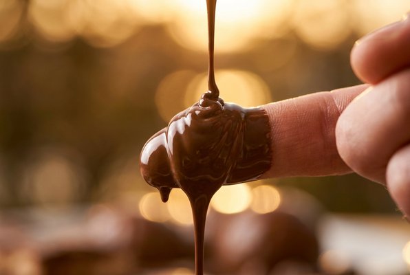 Chocolate melting on fingertips, golden light Chocolate melting on fingertips, golden light