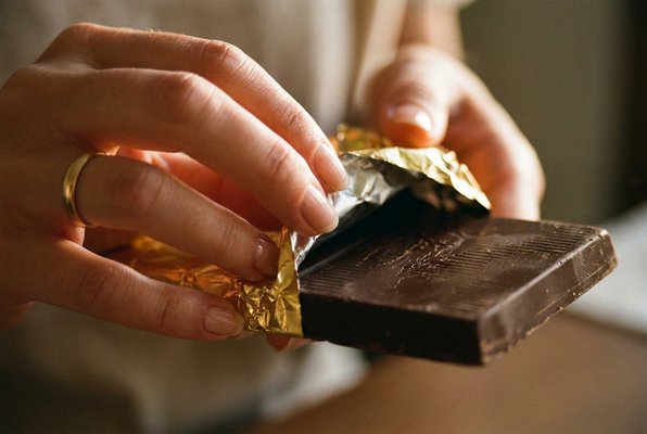 Hands slowly unwrapping a gold NÄKT bar Hands slowly unwrapping a gold NÄKT bar